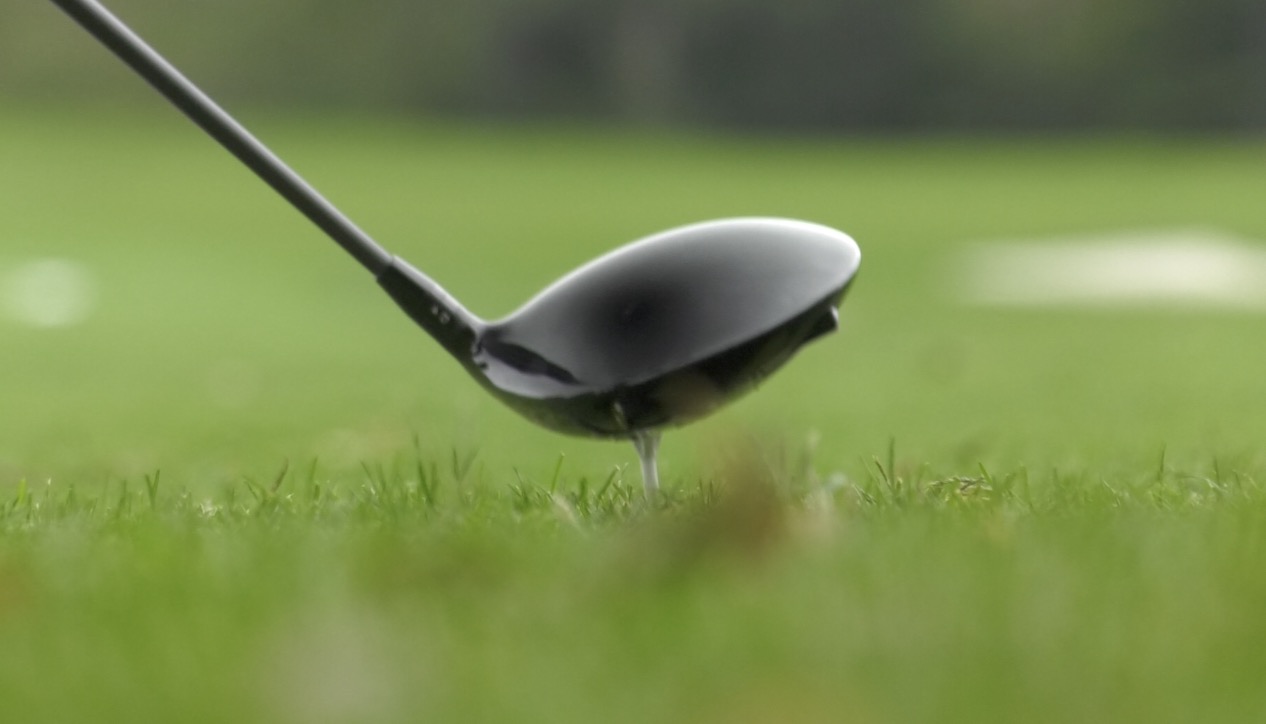 Black golf club touching the grass